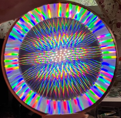 A circular stained glass or prism panel casting dense rainbow light in a radiating pattern